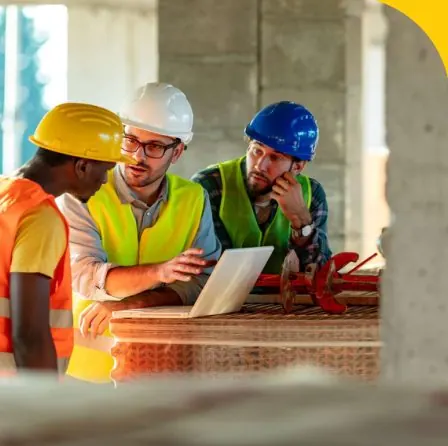 Engineers reviewing plans on a laptop on site